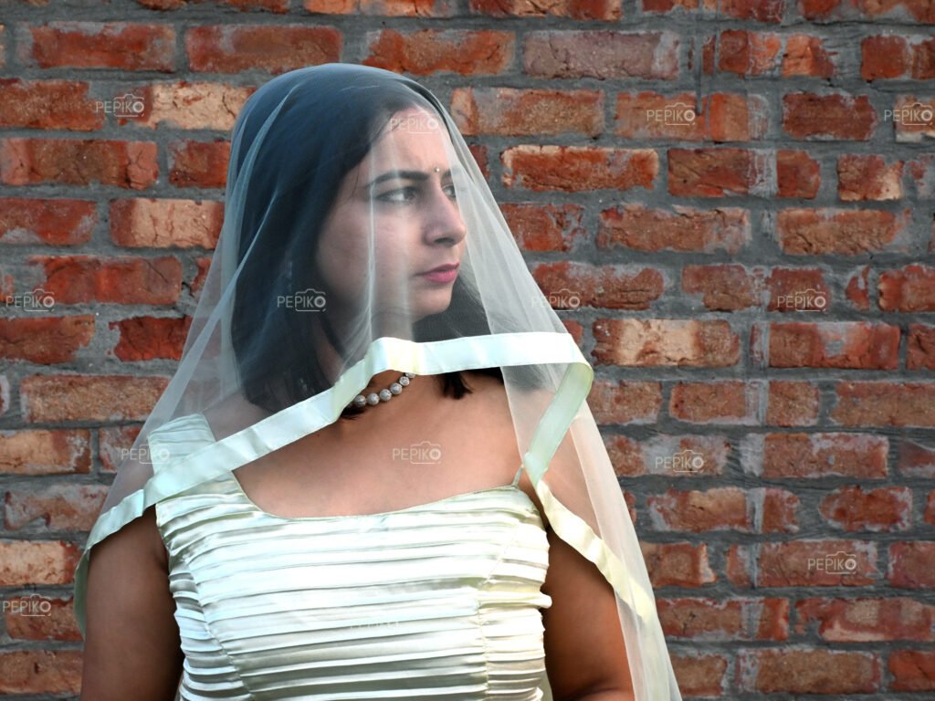 Model wearing light green gown and face covered with sheen